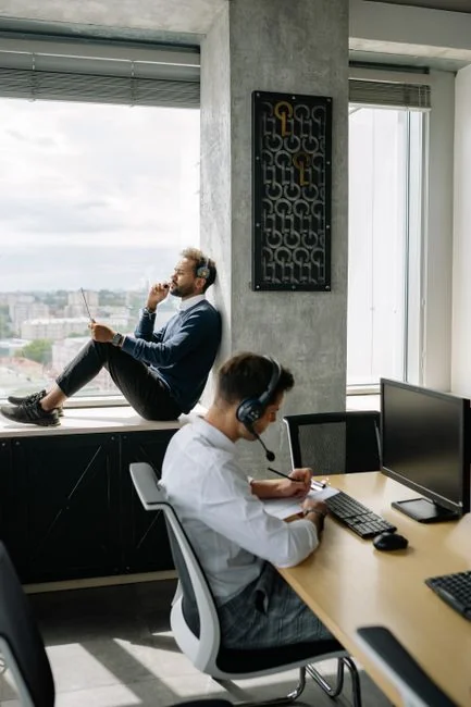 A team of colleagues discussing sales growth using a digital tablet and computer screen in an office setting.